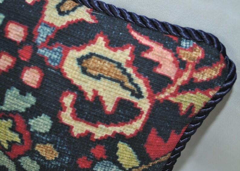 Puede incluir: Primer plano de una almohada azul oscuro con un estampado floral colorido y un ribete azul marino.