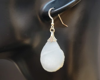 May include: White teardrop-shaped earrings with a silver hook and a silver bail.