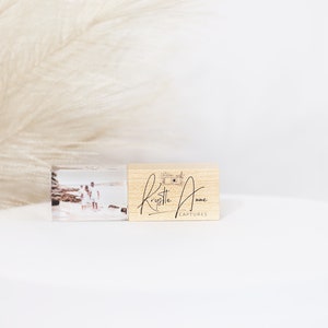 Puede incluir: Una memoria USB de madera con un inserto de foto transparente que muestra a una pareja en la playa. La memoria está grabada con el texto "Krystelle Anne Captures".