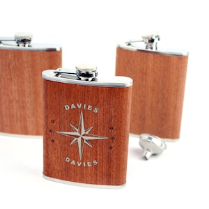 May include: Three stainless steel hip flasks with a wood grain finish. The centre flask has a compass rose design and the name "DAVIES" engraved on it.