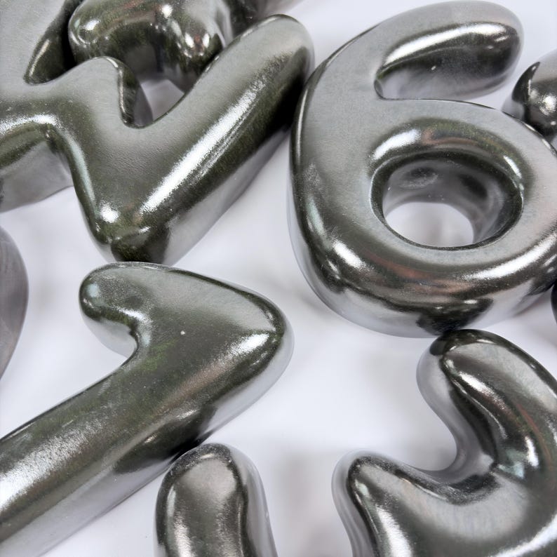 Może przedstawiać: Zbi&oacute;r tr&oacute;jwymiarowych, metalicznych srebrnych cyfr o gładkim, błyszczącym wykończeniu. Widoczne cyfry to duża sz&oacute;stka, czw&oacute;rka i jedynka, wszystkie z zaokrąglonymi krawędziami i odblaskową powierzchnią.