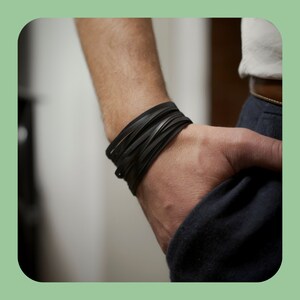 Peut inclure: Un bracelet en cuir noir avec plusieurs couches de cuir tressé.