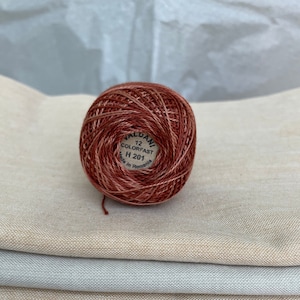May include: A ball of red and orange embroidery floss with a white label that reads "VALDANI 12 COLORFAST H 201 Made in Romania."