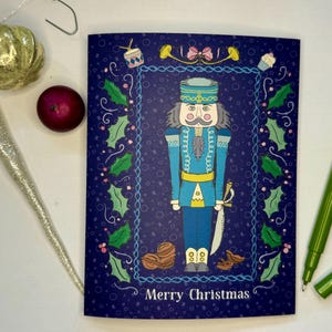 Cartão de Natal, Quebra-Nozes, tamanho A2, em branco por dentro, fundo azul-marinho com cores pastel, saudações natalinas na frente