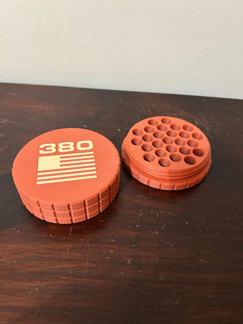 May include: An orange container with the number "380" and a striped design on the lid. The container is open, revealing multiple holes. The container is made of a textured material.