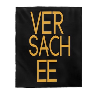 May include: Black throw blanket with the text "VERSACEE" in yellow.