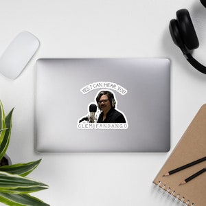 May include: A sticker featuring a man with a microphone and headphones, saying "Yes, I can hear you" and "ClemJFandango".