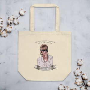 May include: Cream-colored tote bag featuring an illustration of a woman in sunglasses and a white blazer. The text reads "THE LAST MOSQUITO THAT BIT ME HAD TO CHECK INTO THE BETTY FORD CLINIC."
