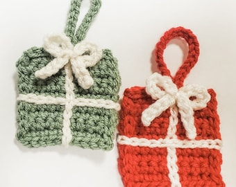 May include: Two crocheted Christmas ornaments shaped like presents. One is green with a white bow and the other is red with a white bow.
