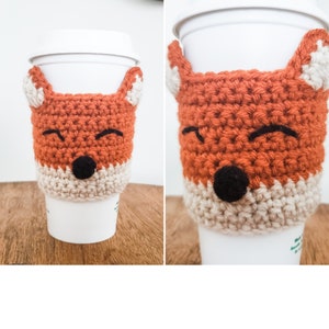Peut inclure: Un manchon de tasse à café en crochet en forme de renard orange et beige avec des yeux et un nez noirs. Le manchon est sur une tasse à café blanche.
