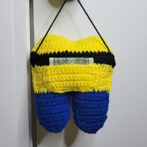 Back image of the Crochet Tooth Fairy Pillow - Yellow guy hanging on a door knob with a dollar in the tooth pocket.