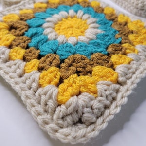 An up close view of the stitches on the crochet granny square bag in blue, yellow, cream and caramel yarn colors.