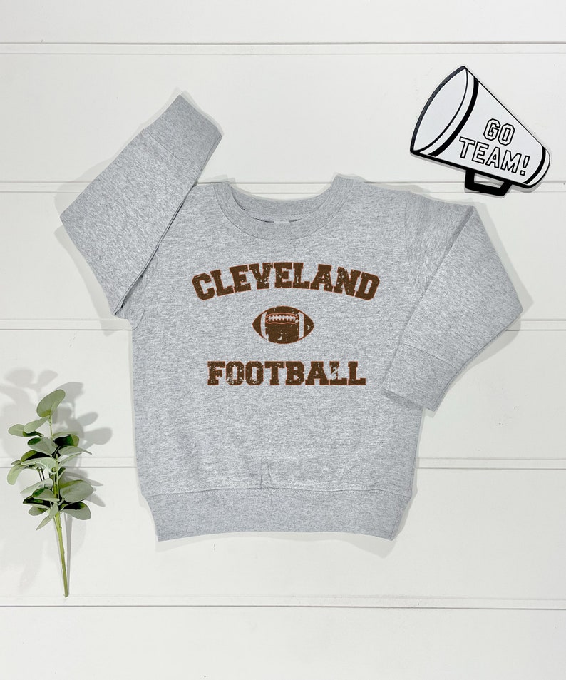 May include: Grey sweatshirt with a brown vintage-style graphic that says "CLEVELAND FOOTBALL" with a football graphic in the centre.