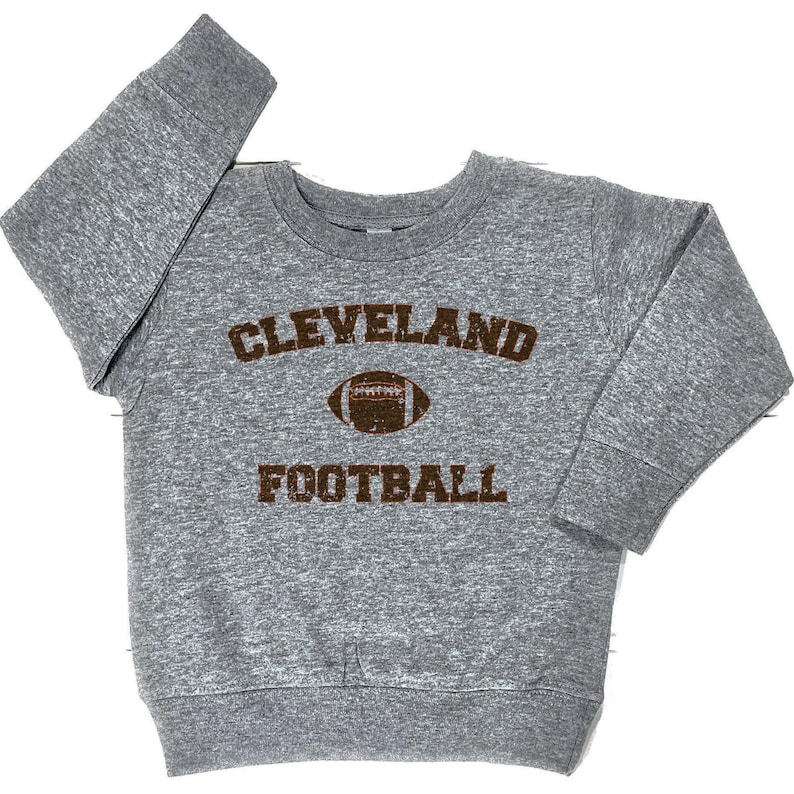 May include: Grey sweatshirt with brown text that reads "CLEVELAND FOOTBALL" with a brown football graphic.