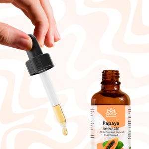 Pu&ograve; includere: Una bottiglia di vetro marrone con un contagocce riempito di un liquido trasparente. La bottiglia ha un'etichetta bianca con il testo "Relaxcation Papaya Seed Oil (100% Pure and Natural) Cold Pressed" e un'immagine di una papaya.