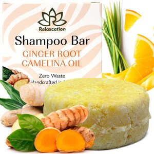 Puede incluir: Una barra de champú amarilla con el texto "Relaxcation Shampoo Bar Ginger Root Camelina Oil Zero Waste Handcrafted in" en el embalaje. La barra está rodeada de raíz de jengibre, raíz de cúrcuma y rodajas de naranja.