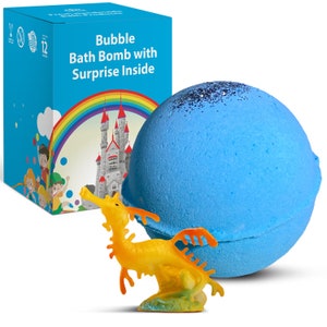 Könnte beinhalten: Eine blaue Badeschaumbombe mit Glitzer, neben einer Schachtel mit dem Text "Bubble Bath Bomb with Surprise Inside". Die Schachtel zeigt einen Regenbogen, ein Schloss und Kinderillustrationen. Ein gelbes Seepferdchen-Spielzeug ist davor.