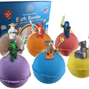 Puede incluir: Cinco bombas de baño de diferentes colores con una minifigura de Lego en la parte superior de cada una. Las bombas de baño son moradas, naranjas, rojas, azules y amarillas. Las minifiguras son un ninja, una serpiente, un dragón, un samurái y un ninja.
