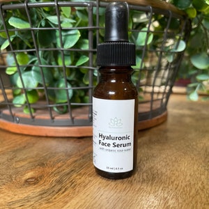 May include: A brown glass bottle with a black dropper top and a white label that reads "Hyaluronic Face Serum with organic rose water". The bottle contains 1.5 fl oz (45 ml) of serum.