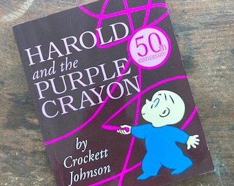 May include: A hardcover book titled "Harold and the Purple Crayon" by Crockett Johnson. The cover is dark brown with white text and a pink design. A cartoon illustration of a character in blue is on the cover, with a 50th Anniversary seal.