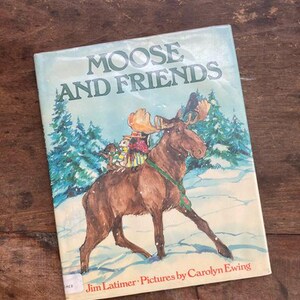 May include: A vintage children's book titled "Moose and Friends" by Jim Latimer with illustrations by Carolyn Ewing. The cover features a brown moose with a red and white scarf walking through a snowy forest with three small animals on its back.