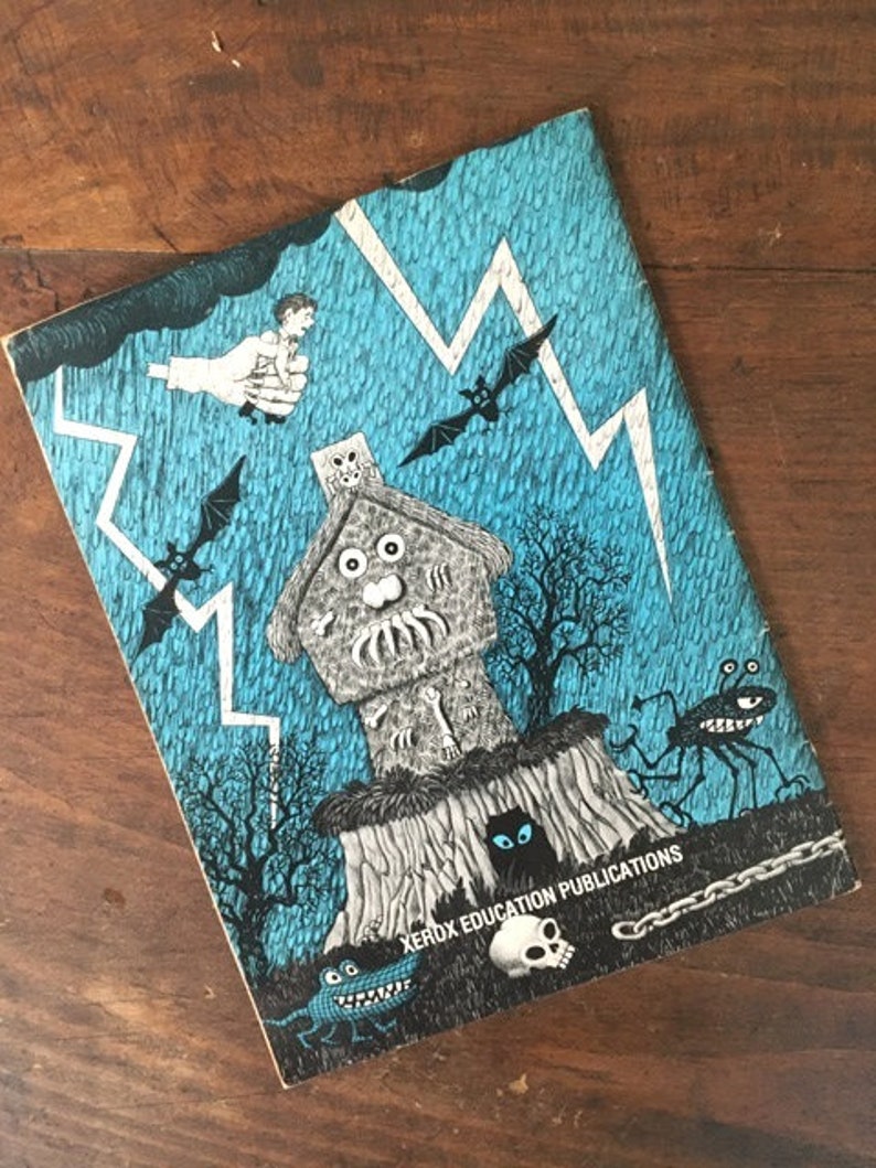 Pode incluir: Uma capa de livro vintage com uma ilustra&ccedil;&atilde;o azul e preta de uma casa assombrada, morcegos, raios e uma caveira. O texto "Xerox Education Publications" est&aacute; impresso na parte inferior da capa.