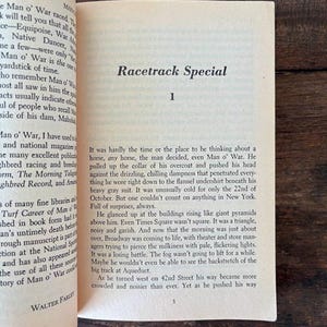 以下が含まれることがあります： 右ページに「Racetrack Special」のタイトルが書かれた開いた本。テキストは黒いフォントで、古びたオフホワイトの紙に書かれています。左ページには競馬に関するテキストがあります。