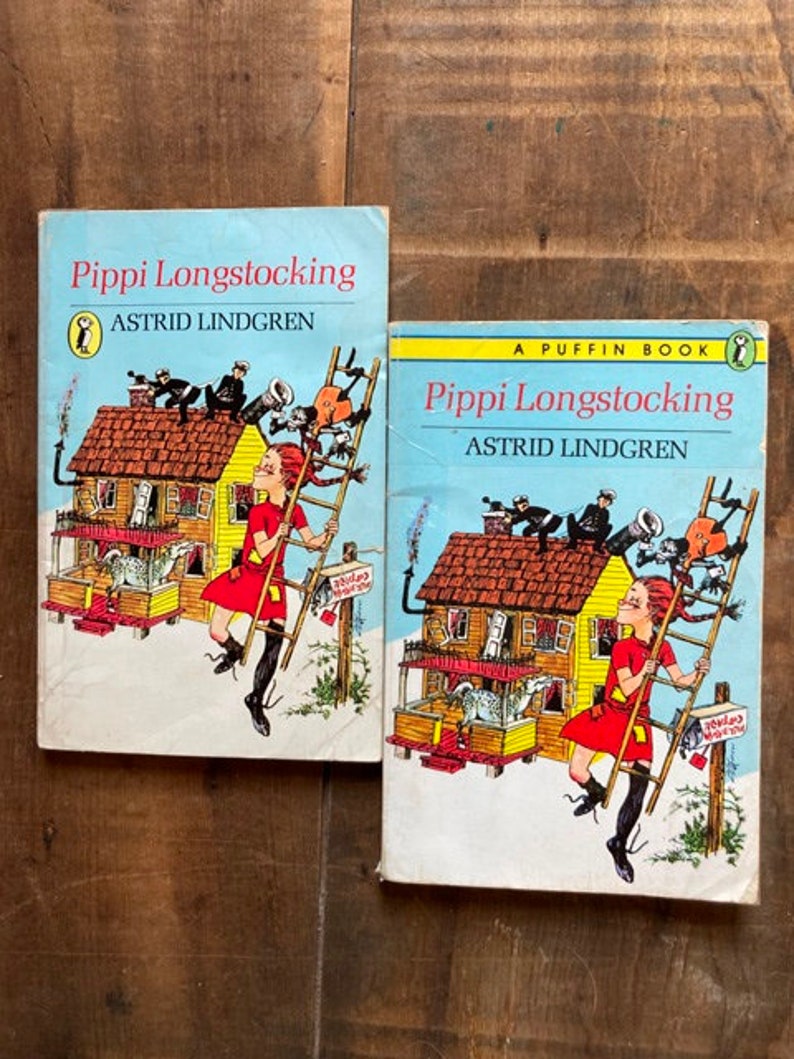 May include: Two vintage paperback books with colorful illustrations of Pippi Longstocking, a fictional character created by Astrid Lindgren. The books are titled "Pippi Longstocking" and "A Puffin Book Pippi Longstocking".