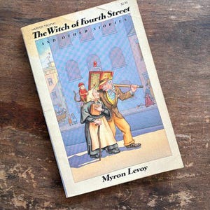 May include: Vintage paperback book titled "The Witch of Fourth Street and Other Stories" by Myron Levoy. The cover features an illustration of two people walking on a street with a blue building background. The book is on a wooden surface.