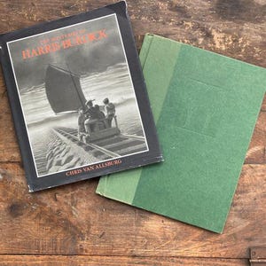 May include: Two hardcover books, one black with white text and the other green. The black book is titled "The Mysteries of Harris Burdick" by Chris Van Allsburg.
