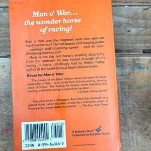 以下が含まれることがあります： オレンジ色の背景に白い文字で「Man o' War... the wonder horse of racing!」と書かれた、ヴィンテージ本の裏表紙。この本は、有名な競走馬の伝記で、Random Houseから出版されました。
