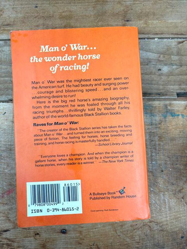 以下が含まれることがあります： オレンジ色の背景に白い文字で「Man o' War... the wonder horse of racing!」と書かれた、ヴィンテージ本の裏表紙。この本は、有名な競走馬の伝記で、Random Houseから出版されました。