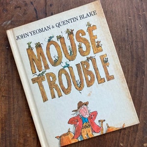 May include: A vintage children's book cover with the title "Mouse Trouble" in large, brown letters. The cover features a cartoon illustration of a man in a cowboy hat and red jacket standing in front of a pile of hay with many mice surrounding him.