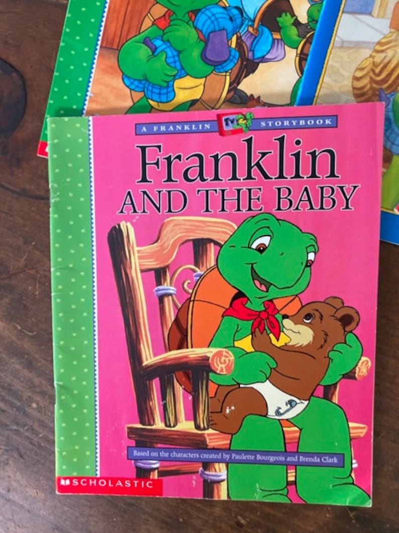 K&ouml;nnte beinhalten: Ein rosa Kinderbuch mit einer gr&uuml;nen Schildkr&ouml;te und einem braunen B&auml;ren auf dem Cover. Der Titel des Buches lautet "Franklin und das Baby". Das Buch ist ein "Franklin"-Bilderbuch, das auf den Figuren von Paulette Bourgeois und Brenda Clark basiert. Das Buch wird von Scholastic herausgegeben.