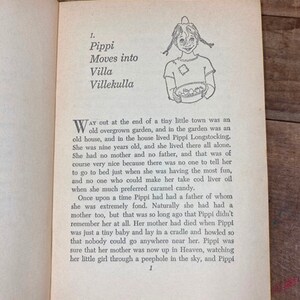 May include: A black and white illustration of a young girl with pigtails holding a bowl of fruit. The text "Pippi Moves into Villa Villekulla" is printed above the illustration. The text describes a young girl who lives alone in a house with an overgrown garden.