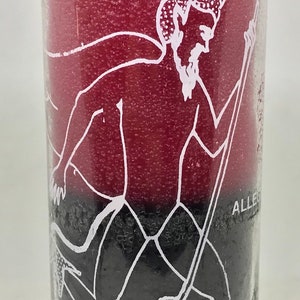 Könnte beinhalten: Eine rote und schwarze Glaskerze mit einem weißen Bild eines Teufels, der mit einer Heugabel rennt. Der Text auf der Kerze lautet "Run Devil Run" und "Your Evil Away".