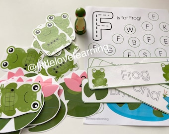 May include: A set of printable educational materials for preschoolers featuring a green frog, lily pads, and the letter F. The printable sheets include a letter tracing activity, a letter matching game, and a word building activity. The text on the sheets reads "F is for Frog!" and "Frog".