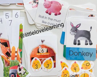 May include: A set of farm animal themed educational cards featuring a barn, chickens, a pig, a donkey, and a cow. The cards have numbers and text that says "Roll in the mud like a pig" and "Donkey". The cards are part of a learning game for children.