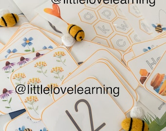 May include: A set of educational cards featuring a bee theme. The cards include numbers, letters, and images of bees and flowers. The cards are designed for children to learn and play. The text on the cards reads "@littlelovelearning".