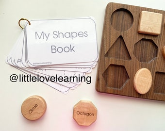 May include: A wooden shape sorting board with a variety of shapes, including a circle, square, triangle, hexagon, and octagon. The board is made of dark wood and has a light wood border. There are also several cards with the names of the shapes on them. The cards are labelled "My Shapes Book" and have the social media handle "@littlelovelearning".