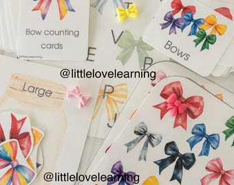 May include: A set of printable educational cards featuring colourful bows. The cards include a rainbow bow, a set of bows in different colours, and a set of bows in different sizes. The cards are labelled "Bow counting cards", "Bows", and "Large".