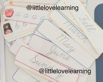 May include: A collection of white flashcards with coloured borders. Some cards display cursive letters and words such as "May" and "Friday." Other cards have illustrations of a bear and an apple. The text "@littlelovelearning" is also visible.