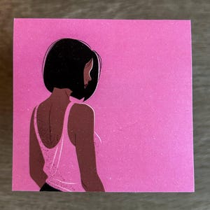 May include: A woman with short black hair is facing away from the viewer. She is wearing a white tank top and has a pink background.