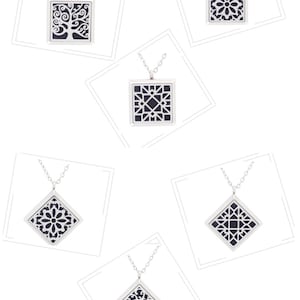 May include: Six silver pendant necklaces with different black and white patterned designs. The pendants are square or diamond shaped.