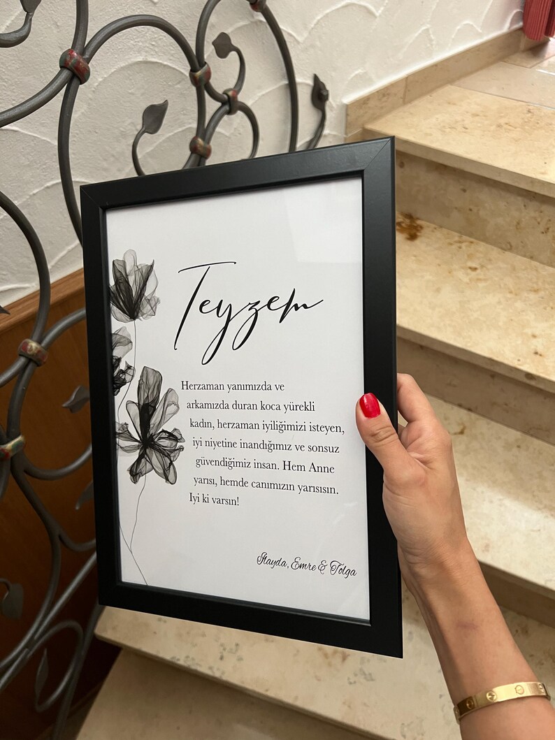 May include: A framed black and white print with a floral design and a handwritten message in Turkish that reads "Teyzem Herzaman yanımızda ve arkamızda duran koca y&uuml;rekli kadın, herzaman iyiliğimizi isteyen, iyi niyetine inandığımız ve sonsuz g&uuml;vendiğimiz insan. Hem Anne yarısı, hemde canımızın yarısısın. lyi ki varsın! Mayda, Emre & Tolga"