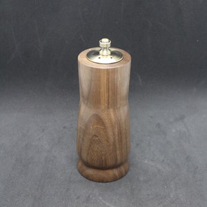 May include: A wooden salt or pepper shaker with a brass top and a round, slightly flared base.