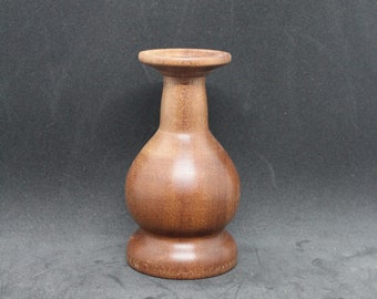 May include: A dark brown wooden vase with a rounded body and a wide, flat top.