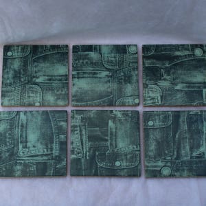 May include: Six square coasters with a denim pattern in shades of blue and green. The coasters are made of ceramic and have a smooth, glossy finish.