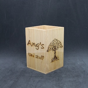 May include: A wooden pencil holder with a Celtic knot tree design and the text "Ang's Uni stuff" engraved on the front.