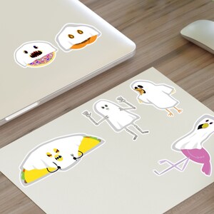 Può includere: Un set di sei adesivi fantasma a tema Halloween. I fantasmi sono vestiti da ciambella, zucca, taco, fenicottero, scheletro e fantasma.